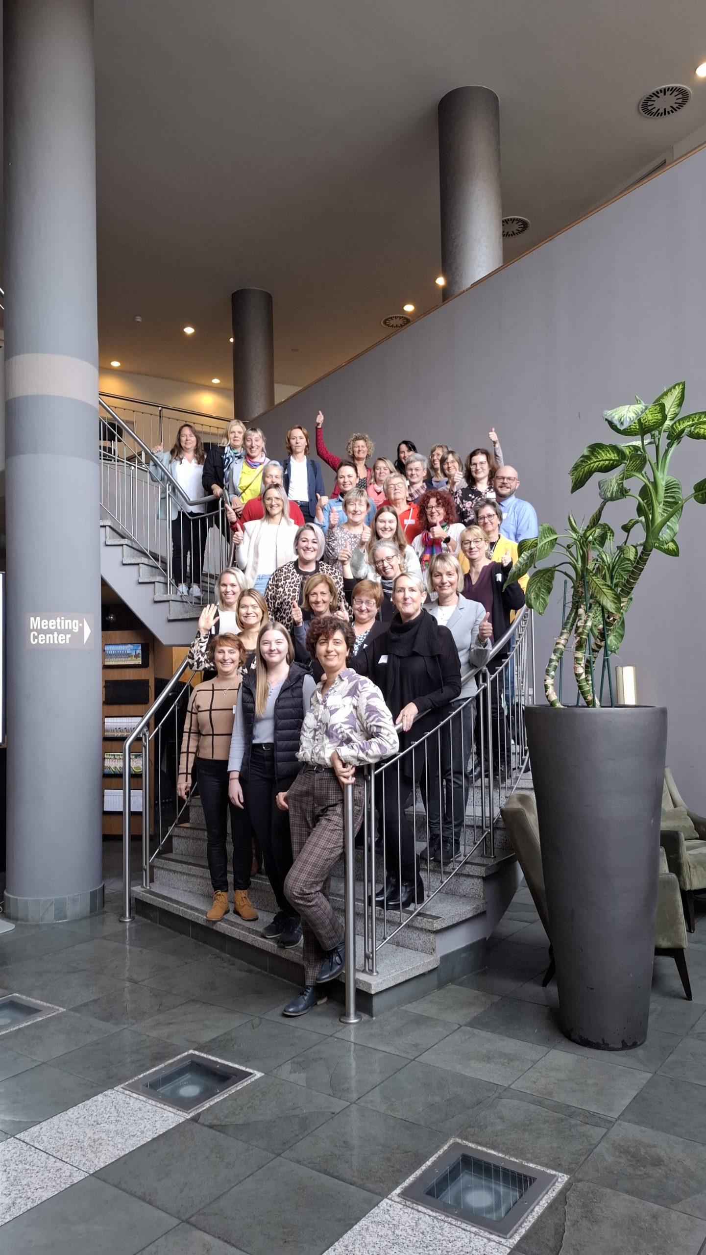 20251113_131901 Die größere Teilnehmergruppe steht auf der Wendeltreppe und lächelt in die Kamera.